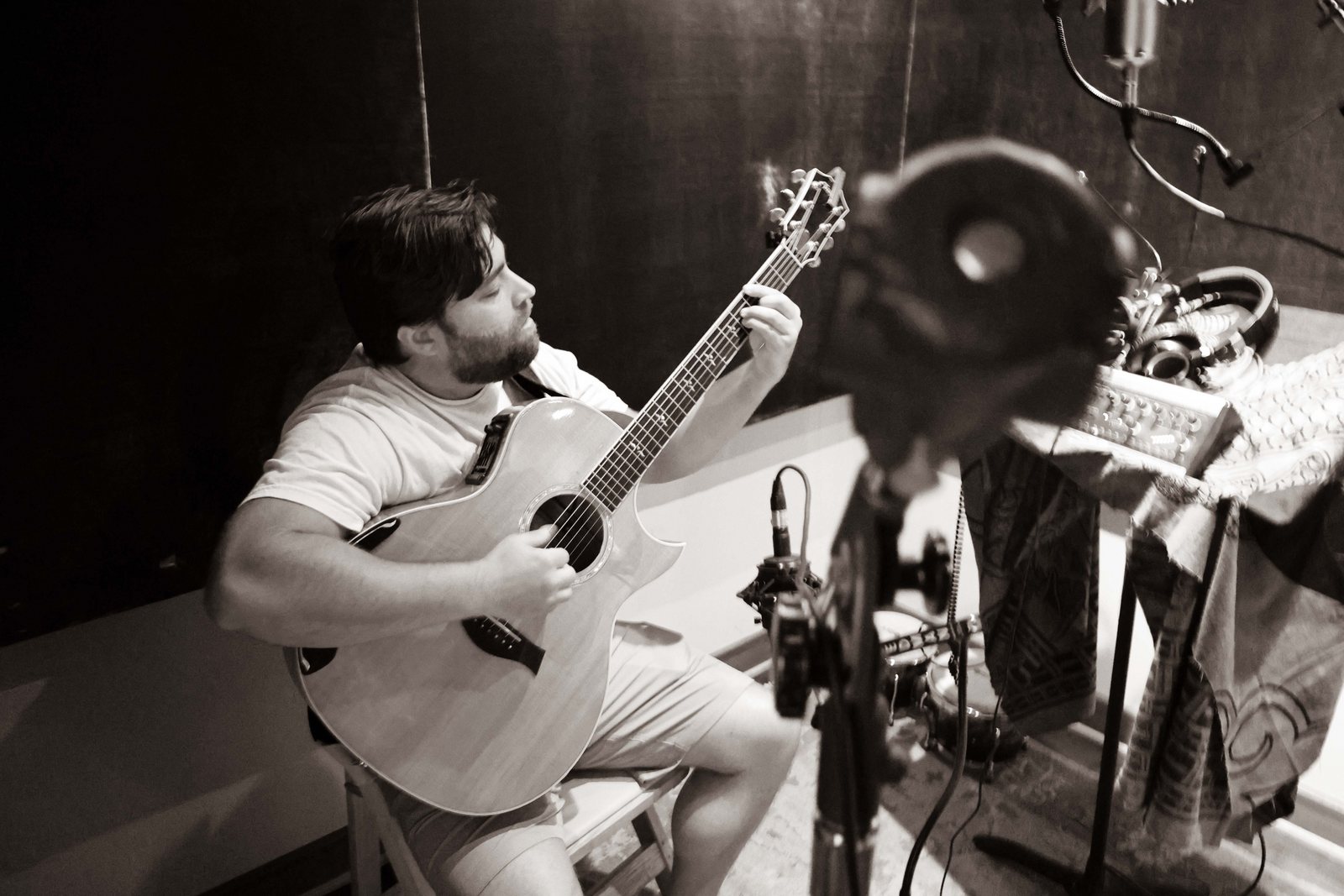 Black-and-white studio photo of Matt Long seated and playing acoustic guitar during a recording session